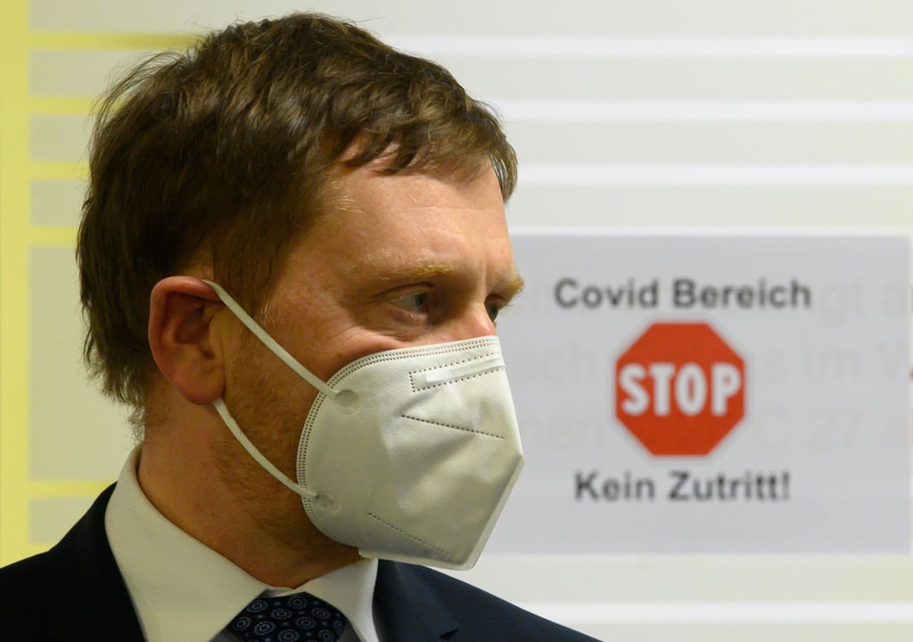 Michael Kretschmer (CDU) vor einem Schild «Covid Bereich Stop Kein Zutritt!». Sachsen wird in Kürze eine neue Corona-Schutzverordnung beschließen.
