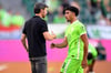 Wolfsburgs Trainer Mark van Bommel klatscht nach der Pokalpartie gegen Preußen Münster mit Omar Marmoush ab.