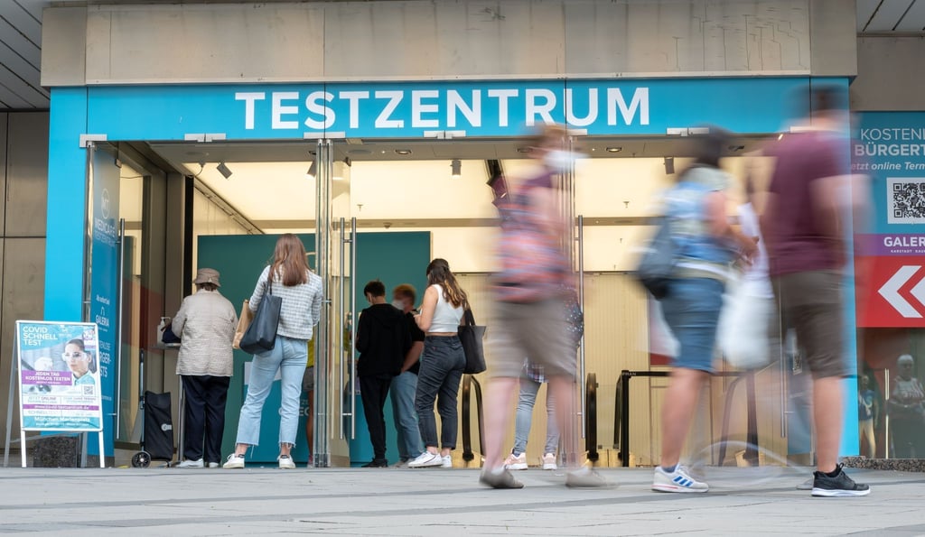 Passanten gehen an einem Corona-Testzentrum in der Münchner Innenstadt vorbei.