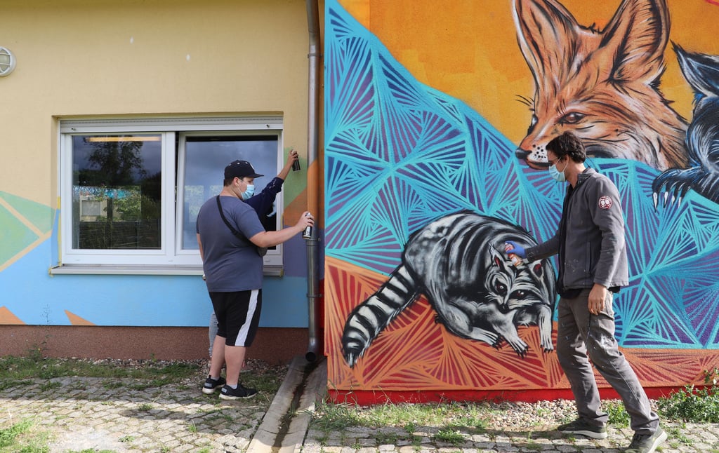 Gemeinsam mit Graffiti-Künstler Christian Grams (re.) gestalten die Teilnehmer des Workshops die Fassade des Pareyer Jugendhauses.