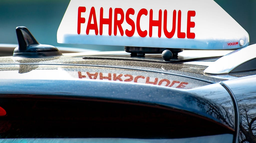 Das Schild einer Fahrschule auf einem Auto.