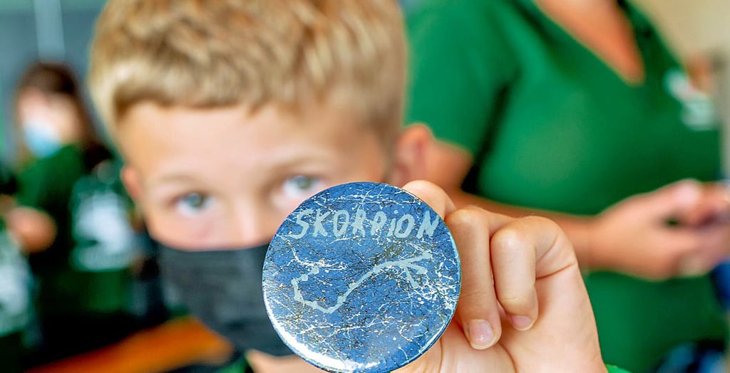 Friedrich, acht Jahre alt, zeigt seinen Button mit dem Sternbild Skorpion, den er mit nach Hause nehmen kann.