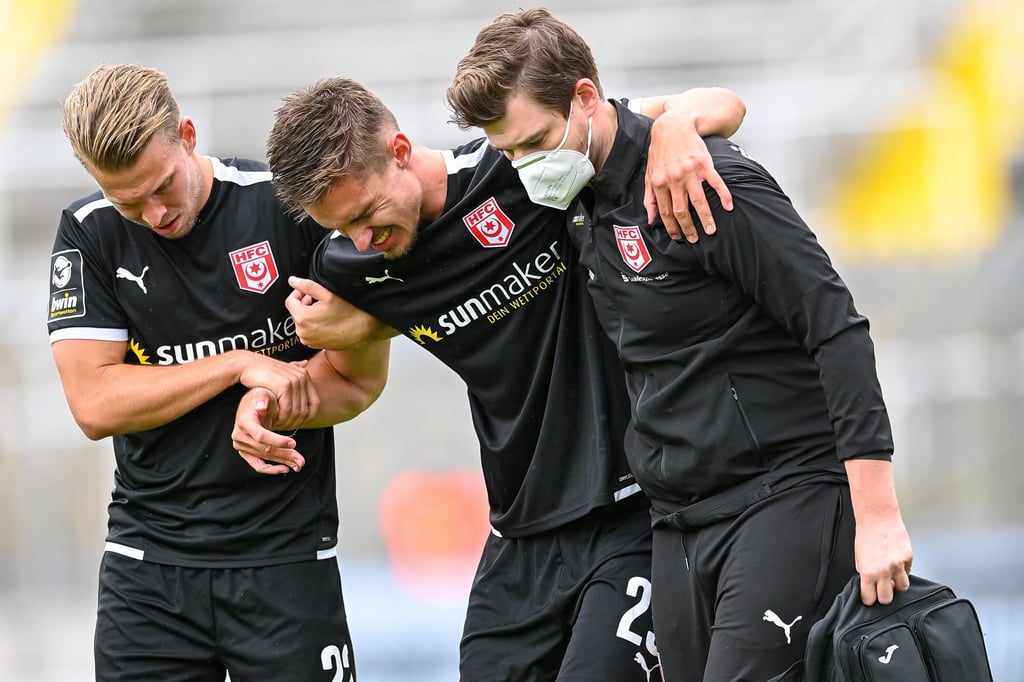 HFC-Spieler Janek Sternberg und ein Betreuer stützen den verletzten Sören Reddemann