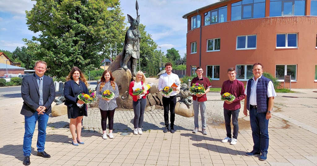Bürgermeister Maik Zedschack (links) und Amtsleiter Meik Noppe (rechts) genießen mit den Auszubildenden (v.l.) Androniki Bafataki, Celine Schröder, Annabell Borck, Alexander Block, Kevin Zahradka und Ole Bienek das gute Wetter am Brunnen der Weisheit.