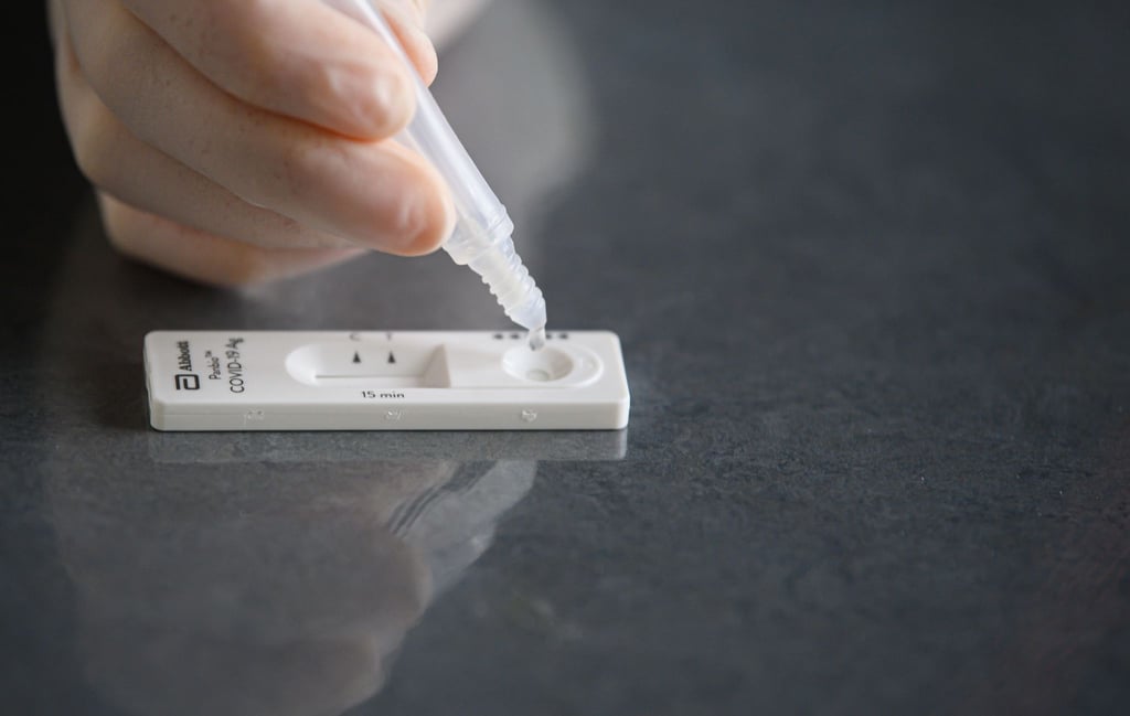 Eine Lösung wird auf eine Testkassette eines Corona-Schnelltests aufgeträufelt.