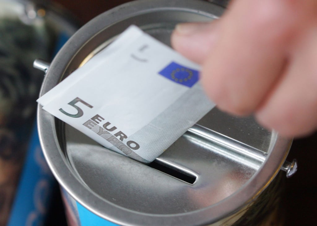Ein Fünf-Euro-Schein wird in eine Spendendose gesteckt. Symbolbild