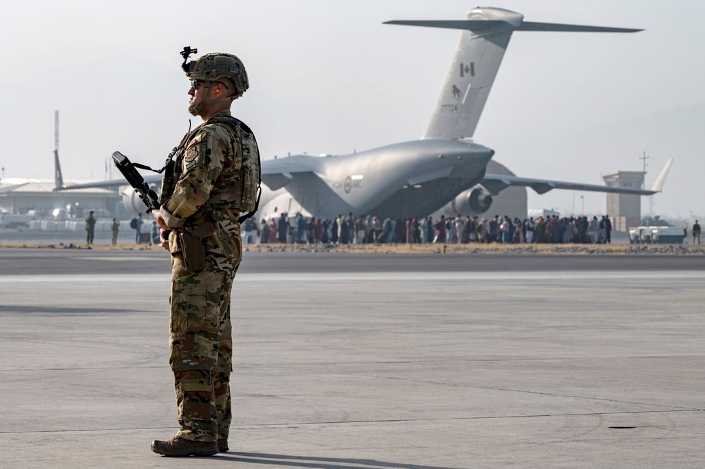 Ein Soldat der US-Luftwaffe steht auf dem Hamid Karzai International Airport in Kabul Wache. Vor den Toren des Flughafens stehen Tausende Menschen.