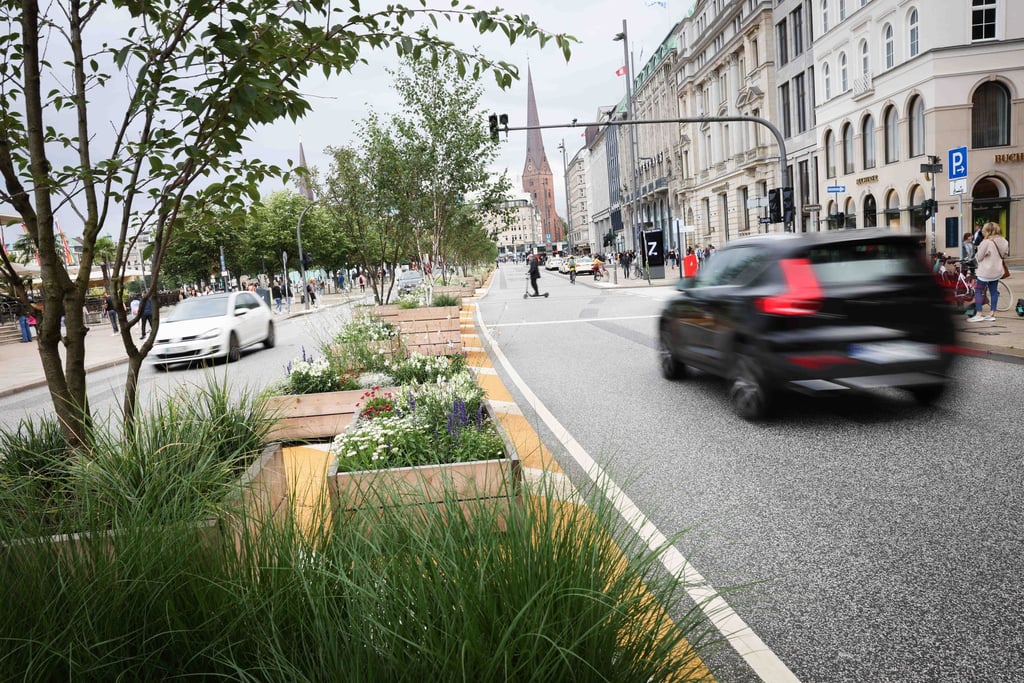 Passanten und vereinzelte Autos sind auf dem Jungfernstieg an der Alster unterwegs.