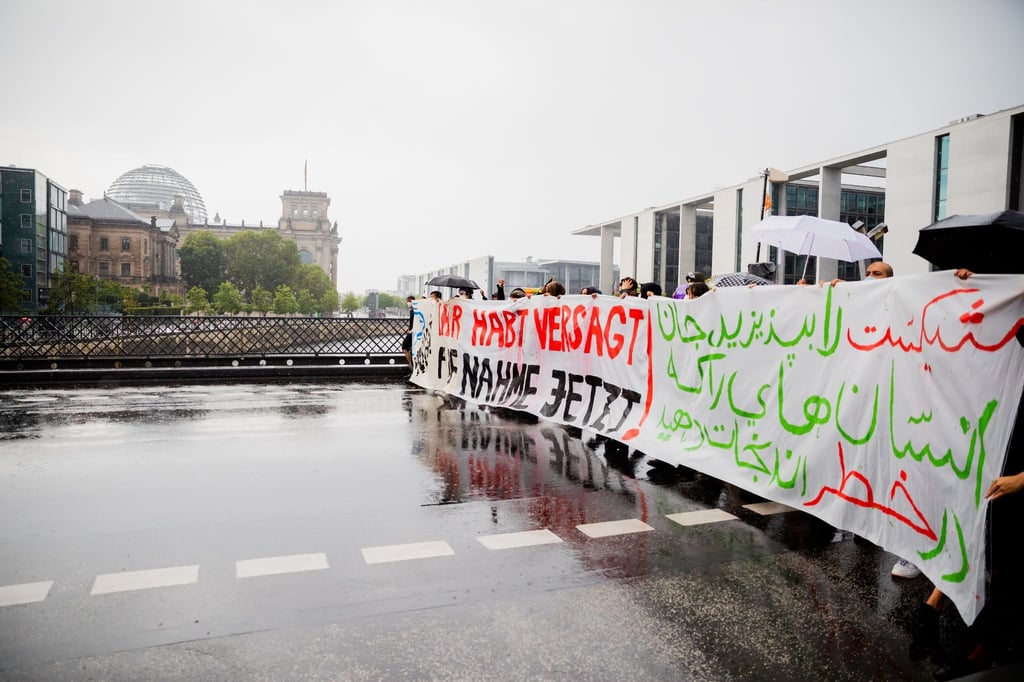 Der Zug einer Demonstration zieht vor dem Reichstagsgebäude über die Marschallbrücke.