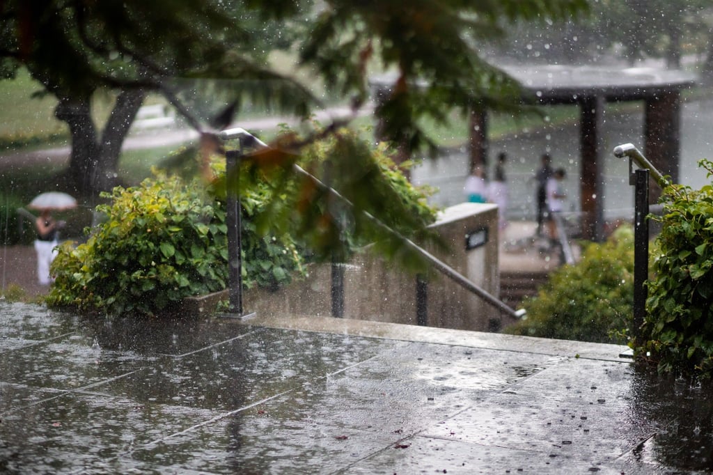 Starker Regen fällt auf eine Terrasse in einem Park.