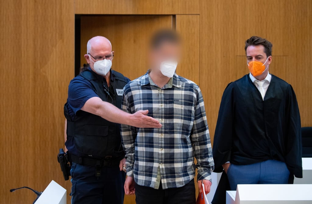 Einer der beiden wegen Mordes angeklagten Männer (M) wird in den Sitzungssaal geführt.