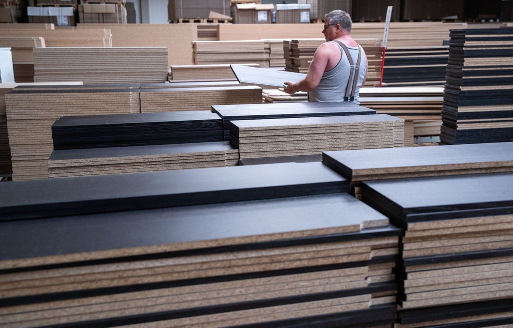 Ein Mitarbeiter sortiert Möbelplatten in einem Werk in Brandenburg.