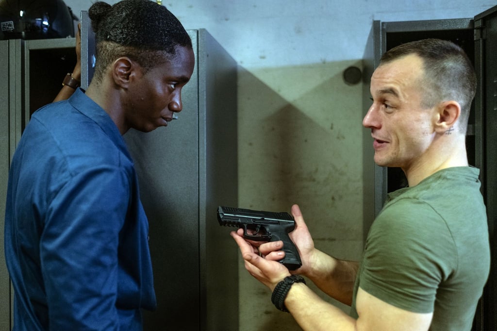 Mario (Paul Wollin, r) prahlt vor seinem Kollegen Man (Emmanuel Ajayi) mit seiner Pistole.