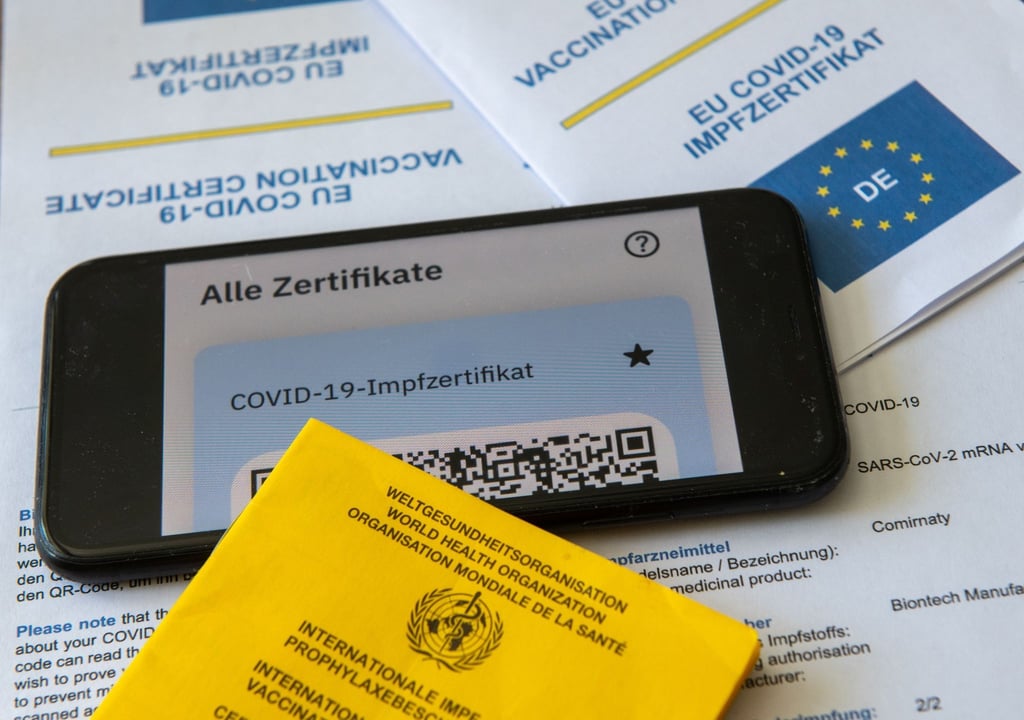 Ein Impfpass und ein Smartphone, auf dem die CovPass-App geöffnet ist.
