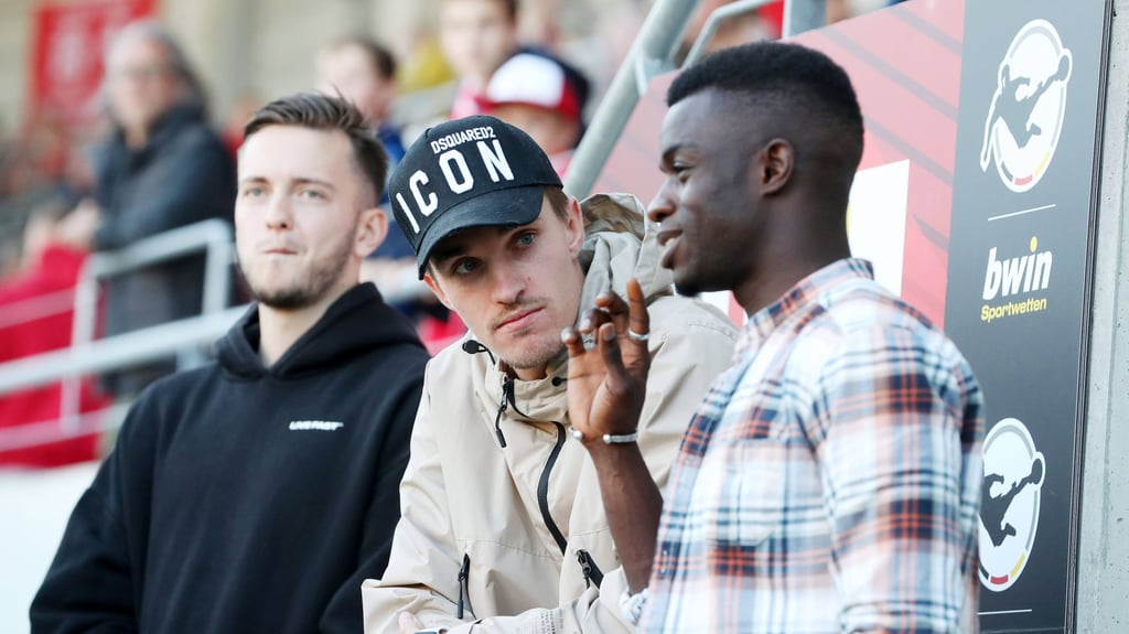 Der verletzte Sören Reddemann (m.) als Zuschauer mit seinen Teamkollegen Jannes Vollert (l.) und Kebba Badjie (r.) im Leuna-Chemie-Stadion.