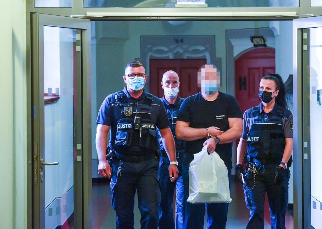 Mit Hand- und Fußfesseln aus der Untersuchungshaft vorgeführt: Justizbedienstete bringen den Angeklagten (3. v. l.) in den Gerichtssaal.