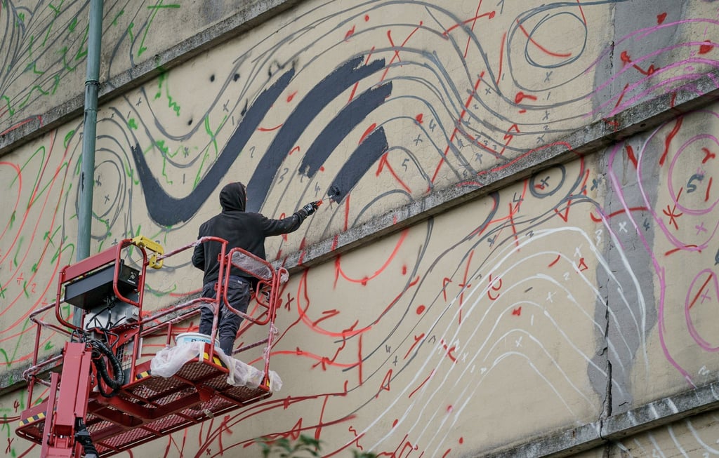 Der Hamburger Urban Art-Künstler „1010“ arbeitet auf einem Hubsteiger an einem riesigen Wandbild am Hochbunker im Stadtteil Altona.