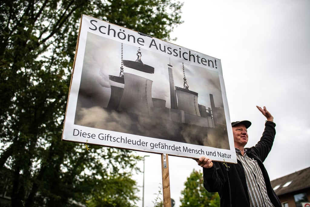Vor der Verhandlung beim Oberverwaltungsgericht um das Kohlekraftwerk Datteln 4 steht ein Klimaaktivist und protestiert mit einem Plakat.