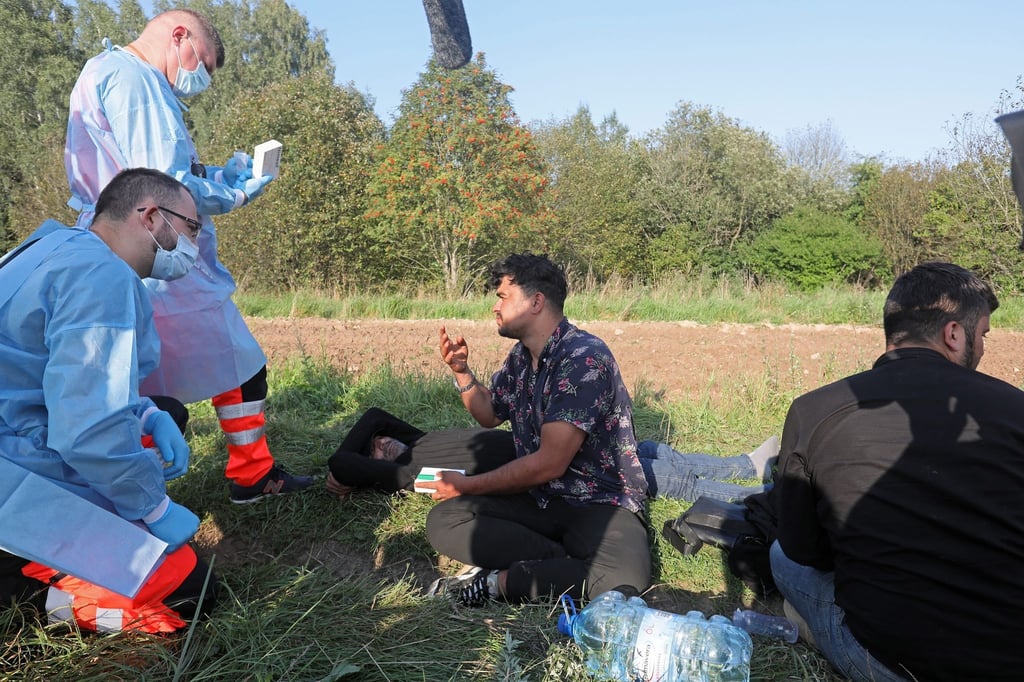 Sanitäter sprechen mit der Gruppe von Flüchtlingen an der polnisch-belarussischen Grenze.