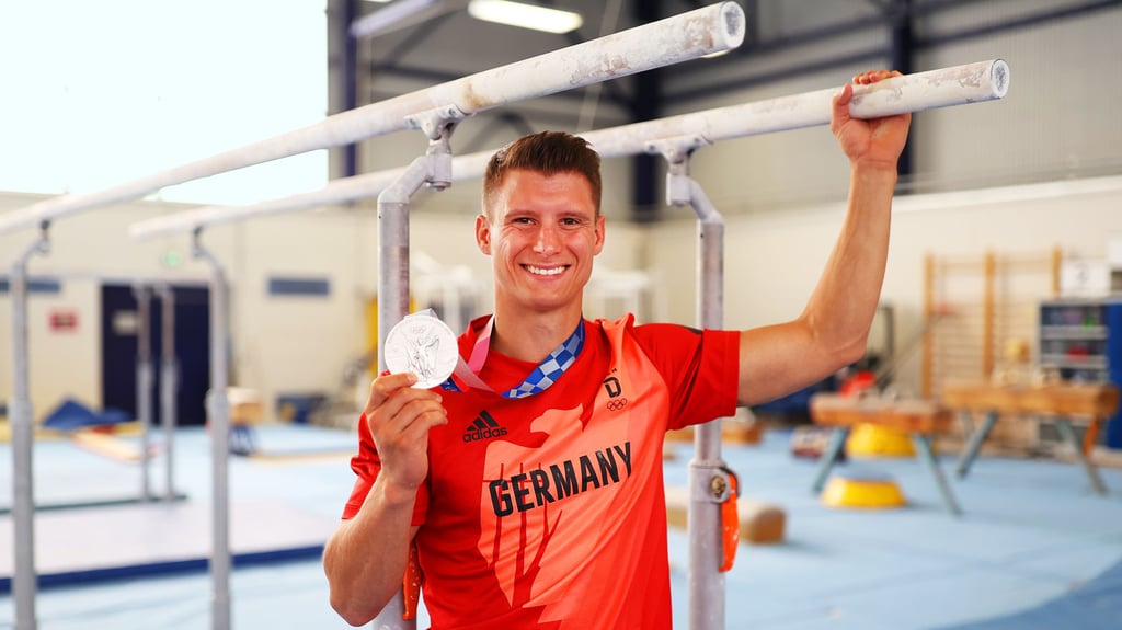 Lukas Dauser mit der in Tokio gewonnenen Silbermedaille an seinem Erfolgsgerät, dem Barren