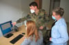 Ein Soldat aus dem Organisationsbereich Cyber-und Informationsraum weist Mitarbeiterinnen der Verwaltung in neuen Arbeitsplatzrechner ein