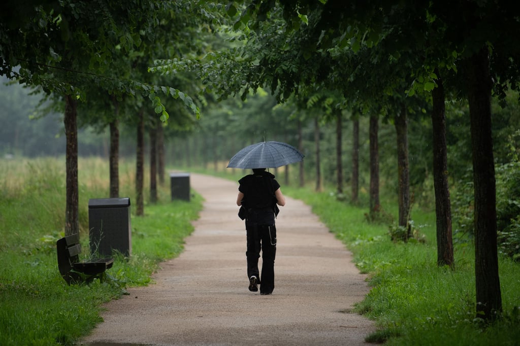 Ein Mann geht mit Regenschirm spazieren.