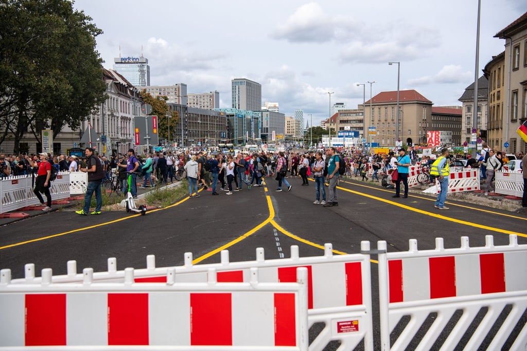 Aus Protest gegen die Corona-Politik überqueren Demonstranten eine abgesperrte Straße.