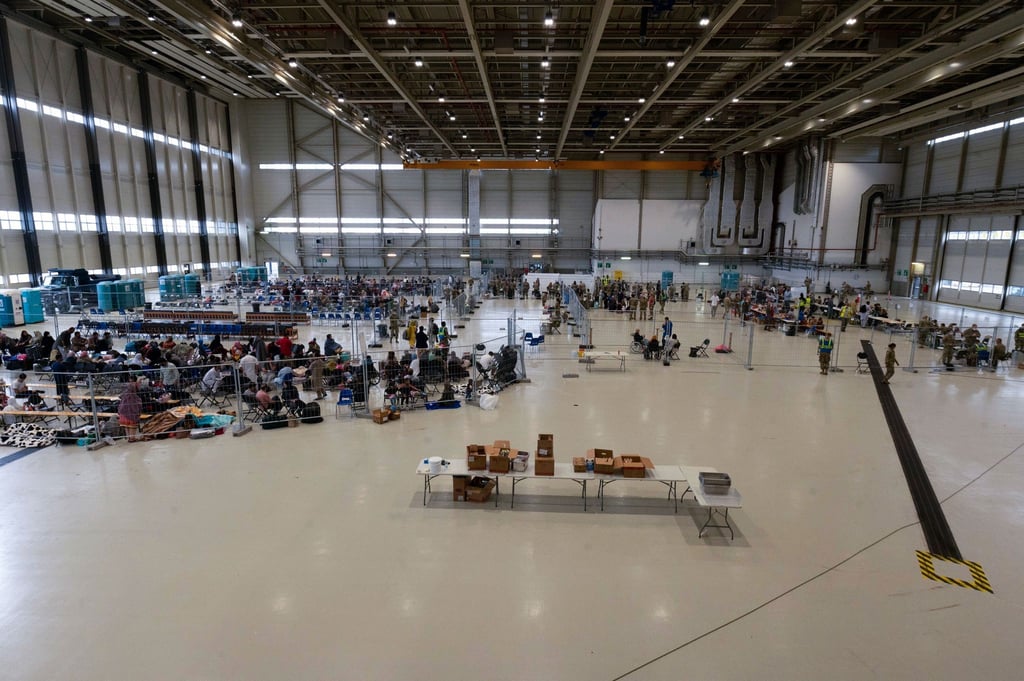 Für die Abfertigung von Passagieren, die zu ihrem nächsten Ziel transportiert werden sollen, wurde ein Wartungshangar in einen kleinen internationalen Flughafen umgewandelt.