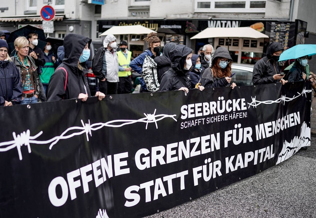 Teilnehmer einer Afghanistan-Solidaritäts-Demonstration im Hamburger Stadtteil St. Georg tragen ein Banner mit der Aufschrift „Offene Grenzen für Menschen statt für Kapital“ vor sich.