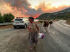 Eine Frau flieht mit ihren Tieren im türkischen Bodrum vor einem sich ausbreitenden Waldbrand.