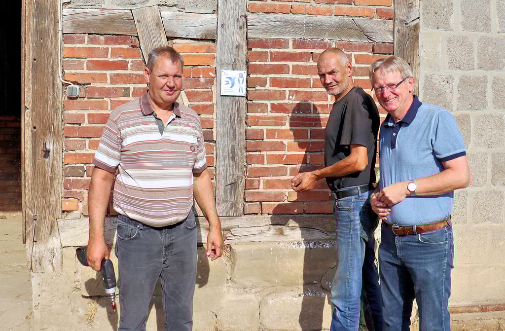 Axel Heine, Thomas Howard und Gerhard Timme (von links) haben am Balken des Pferdestalls auf dem Bauernhof in Dedeleben, in dem hunderte Schwalben leben, die Plakette ?Schwalbenfreundliches Haus" angebracht.