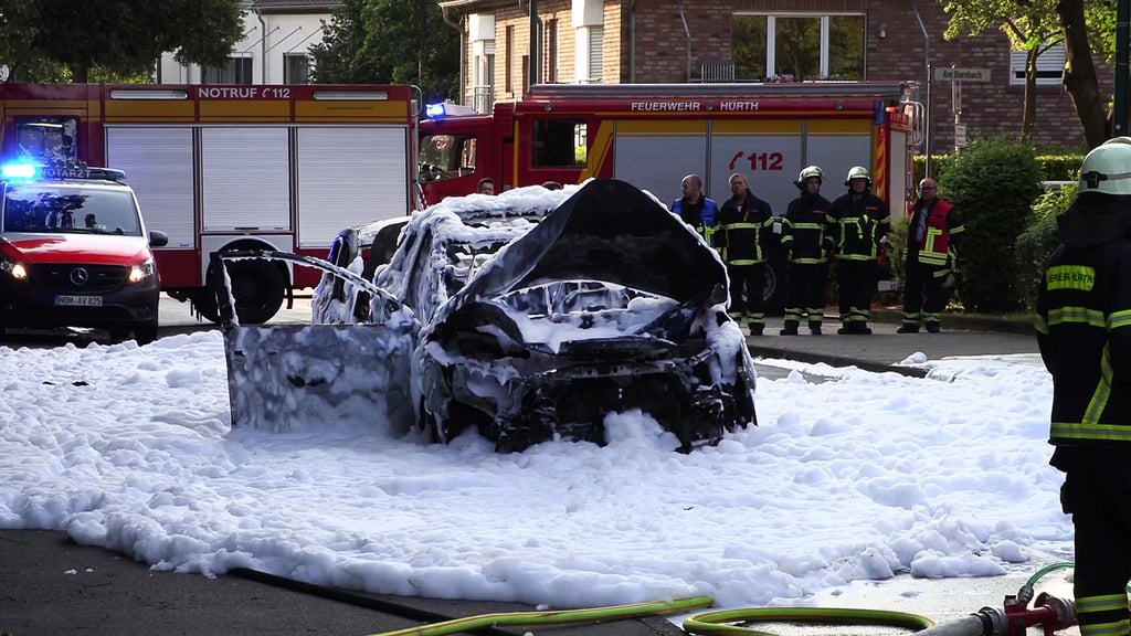 Vom Löschschaum bedeckt steht ein Auto nach einer Explosion auf der Straße im nordrhein-westfälischen Hürth.