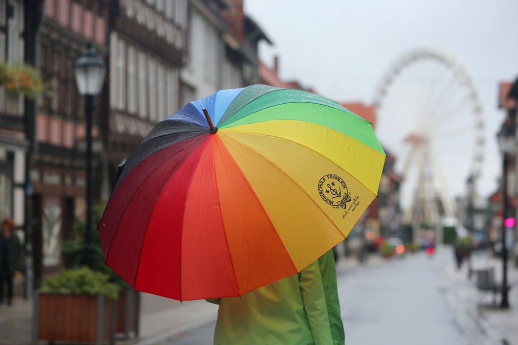 Passanten gehen bei Regenwetter durch die Fußgängerzone von Wernigerode in Sachsen-Anhalt.