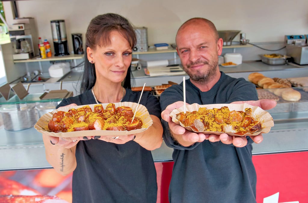 Mandy Ziegler und Michel Benny vom Grillimbiss Merkel am Globus Baumarkt, mit zwei unterschiedlichen Currywürsten aus dem Sortiment.