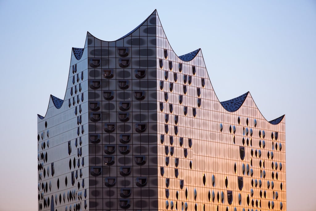 Die gläserne Fassade der Elbphilharmonie wird von der aufgehenden Sonne beleuchtet.