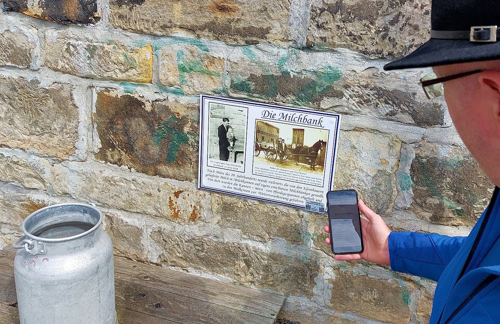 Niklas Nienstedt testet den QR-Code an der Milchbank. Dank ihm, seiner Frau Annett und der schriftlichen Zuarbeit von Steffen Wetterling können Besucher über ihr Handy nun allerlei Wissenswertes zu den Stationen am Altstadtrundweg in Oebisfelde erfahren.