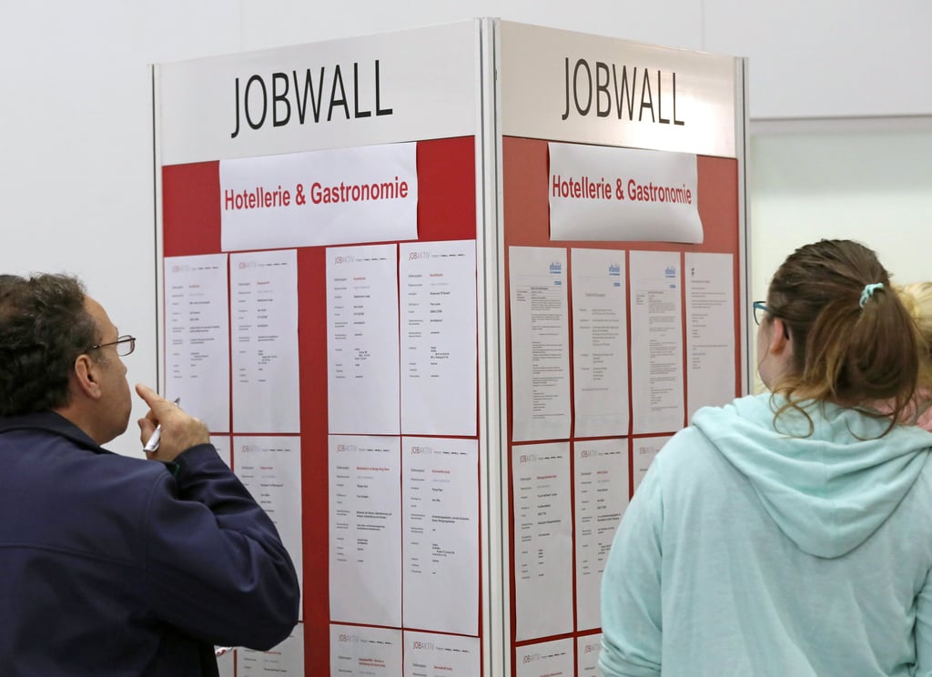 Menschen stehen an einer „Jobwall“ mit Arbeitsangeboten in der Gastronomie.