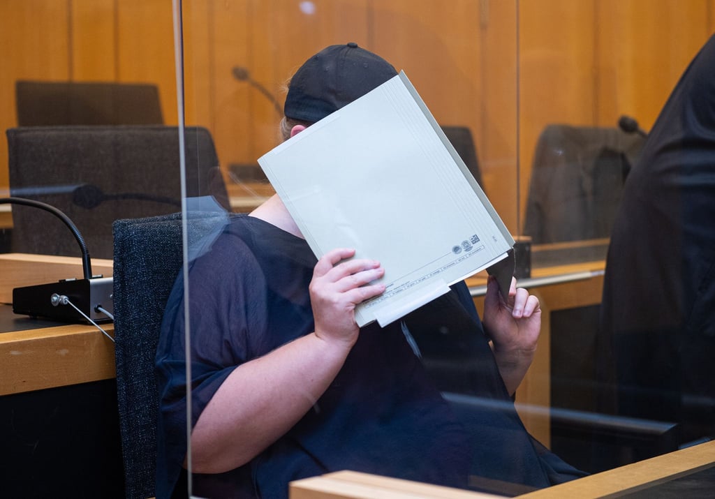 Zu Beginn des Prozesses im Missbrauchskomplex Münster sitzt die Mutter eines Opfers im Landgericht Münster und verdeckt ihr Gesicht mit einer Mappe.