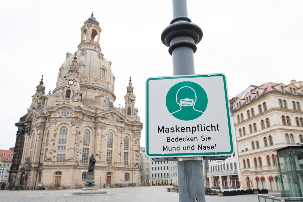 Ein Hinweisschild auf die Maskenpflicht hängt auf dem Neumarkt vor der Frauenkirche.