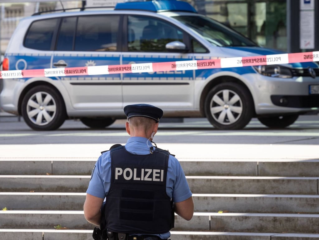 Illustration: Ein Polizist steht nach einer Bombendrohung vor einem abgesperrten Beich.