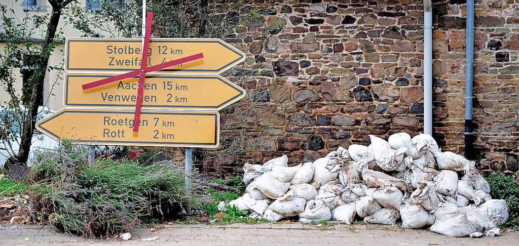Sandsäcke liegen neben Straßenschildern: Der Ort Mulartshütte nahe Aachen ist schwer vom Hochwasser in Nordrhein-Westfalen getroffen.