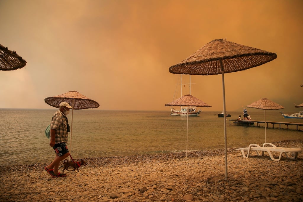 Ein Mann mit Hund am Strand in der Ferienregion Bodrum: In Teilen der Türkei toben heftige Brände.