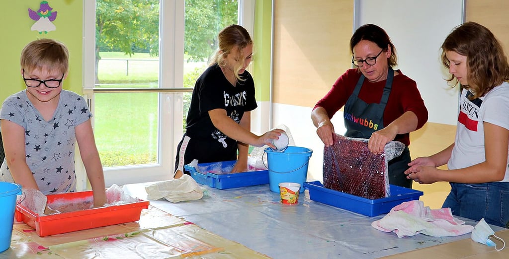 Kunstlehrerin Daniela Meinecke (2. v. re.) zeigte Kindern auch in diesem Jahr wieder im Rahmen der Kreativwerkstatt, wie man Filz herstellt. Susan, Sky und Vivien (v. li.) waren beim Nassfilzen mit viel Eifer und Ausdauer dabei.