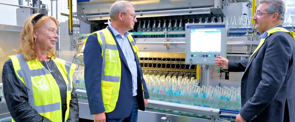 Nicola (links) und Ralph Weitemeyer (rechts) erläutern IHK-Vizepräsident Nils Appelt die automatische Waschanlage für Mehrweg-Glasflaschen der Harzer Mineralquellen GmbH in Blankenburg. Der computergestützt arbeitende Automat wurde erst kürzlich mit einer Laugenfilteranlage ausgerüstet.