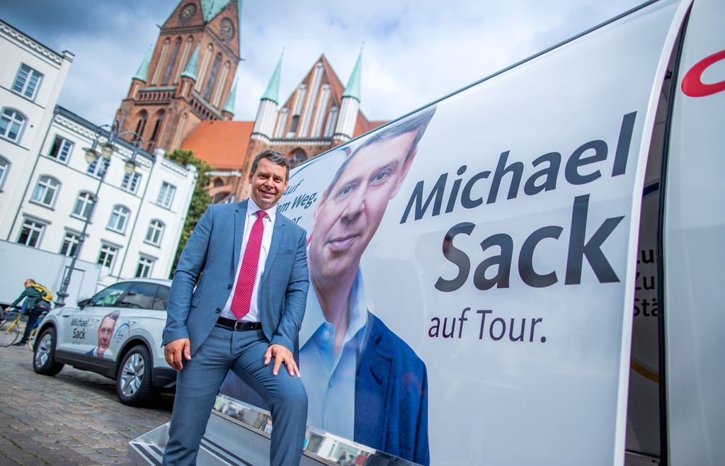 CDU-Spitzenkandidat Michael Sack steht beim Wahlkampf vor dem Tourbus.