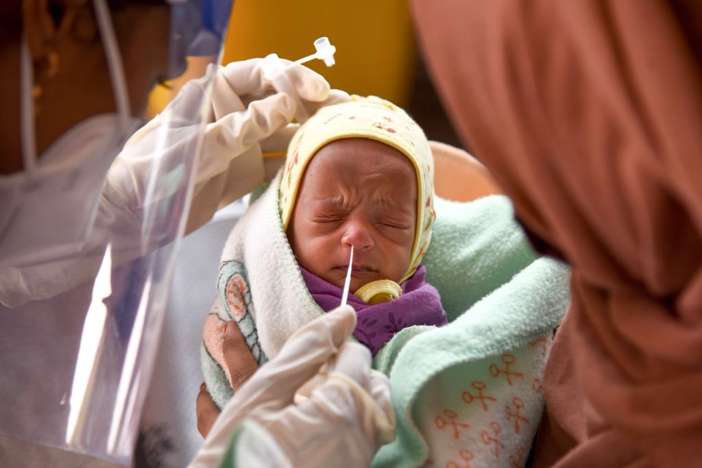 Eine Medizinerin entnimmt einem Baby in einem Krankenhaus einen Nasenabstrich für einen Corona-Test.