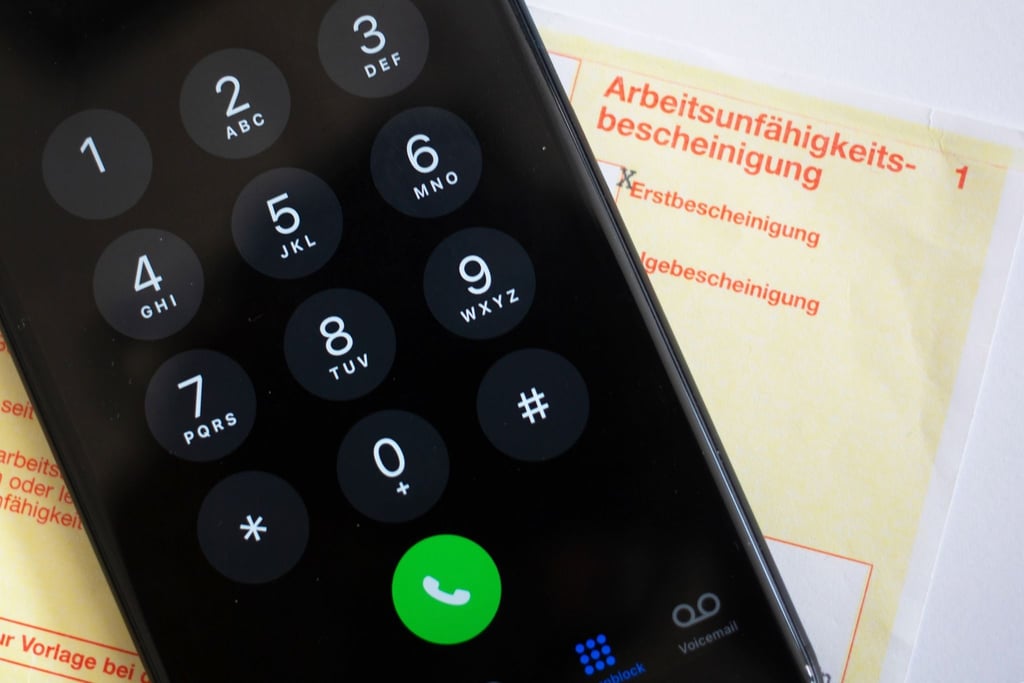 Ein Handy liegt auf einer Arbeitsunfähigkeitsbescheinigung.