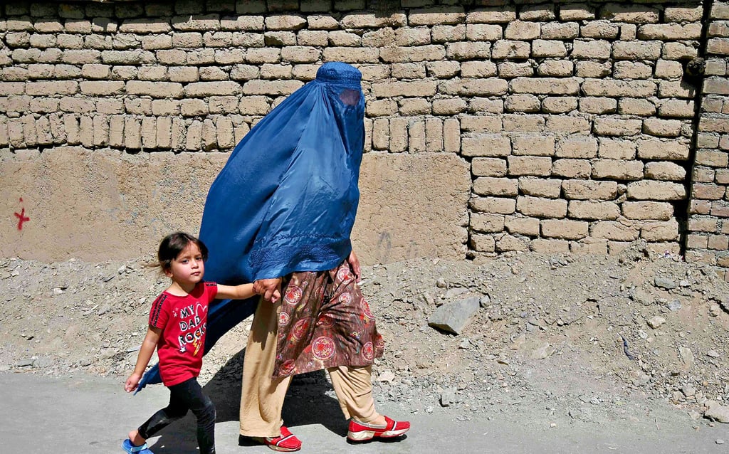 Nach der Machtübernahme der Taliban: Eine verschleierte Frau ist am Donnerstag mit ihrem Kind in Kabul unterwegs.