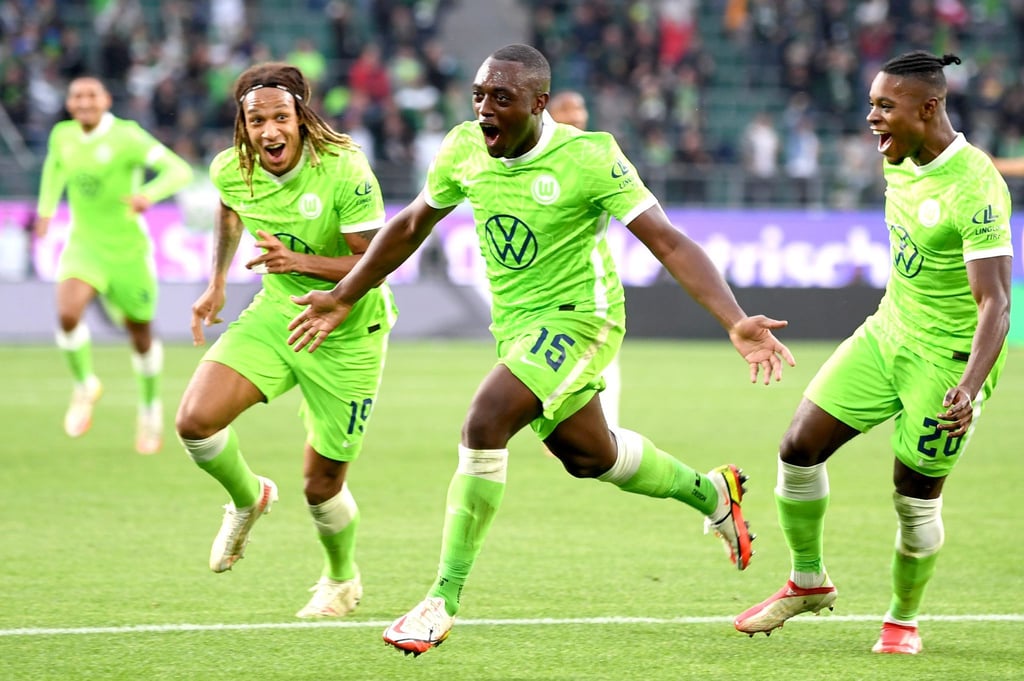 Wolfsburgs Jerome Roussillon (M) jubelt nach seinem Treffer zum 1:0 mit seinen Teamkollegen Kevin Mbabu (l) und Ridle Baku (r).