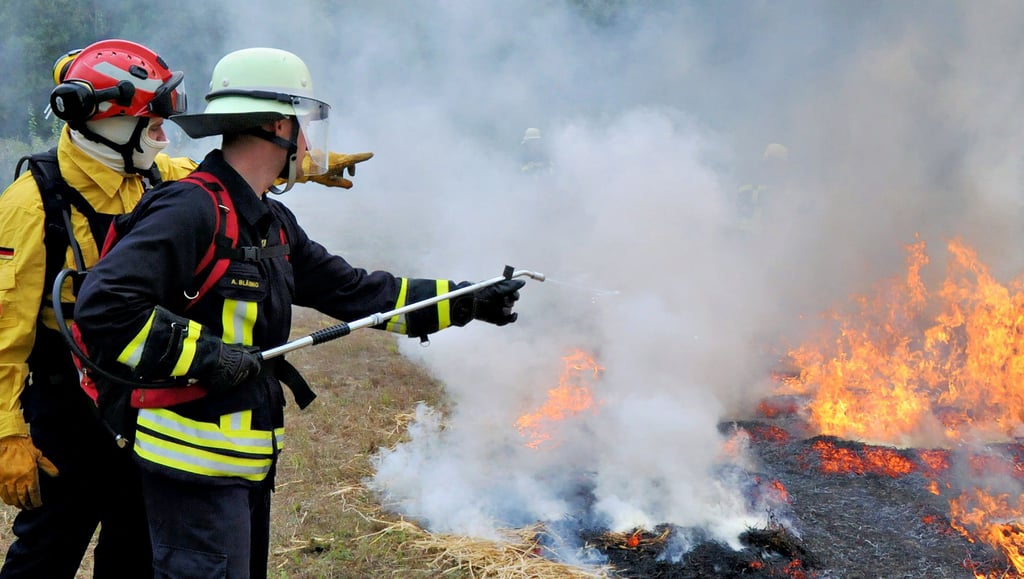 Der richtige Umgang und Einsatz von einfachen Mitteln, zu dem auch der Wasserrucksack gehört, wird auf einer brennenden Fläche bei Wieglitz geübt. Kay Lütten (l.) gibt dazu einem Feuerwehrmann aus Böddensell die fachlichen Anleitungen.